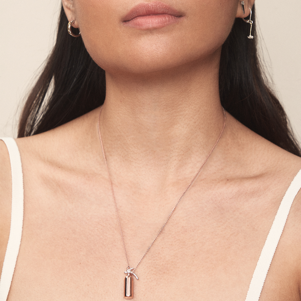 Model wearing Extinguish Hate rose gold-plated Fire Extinguisher necklace by Pavé The Way® Jewelry